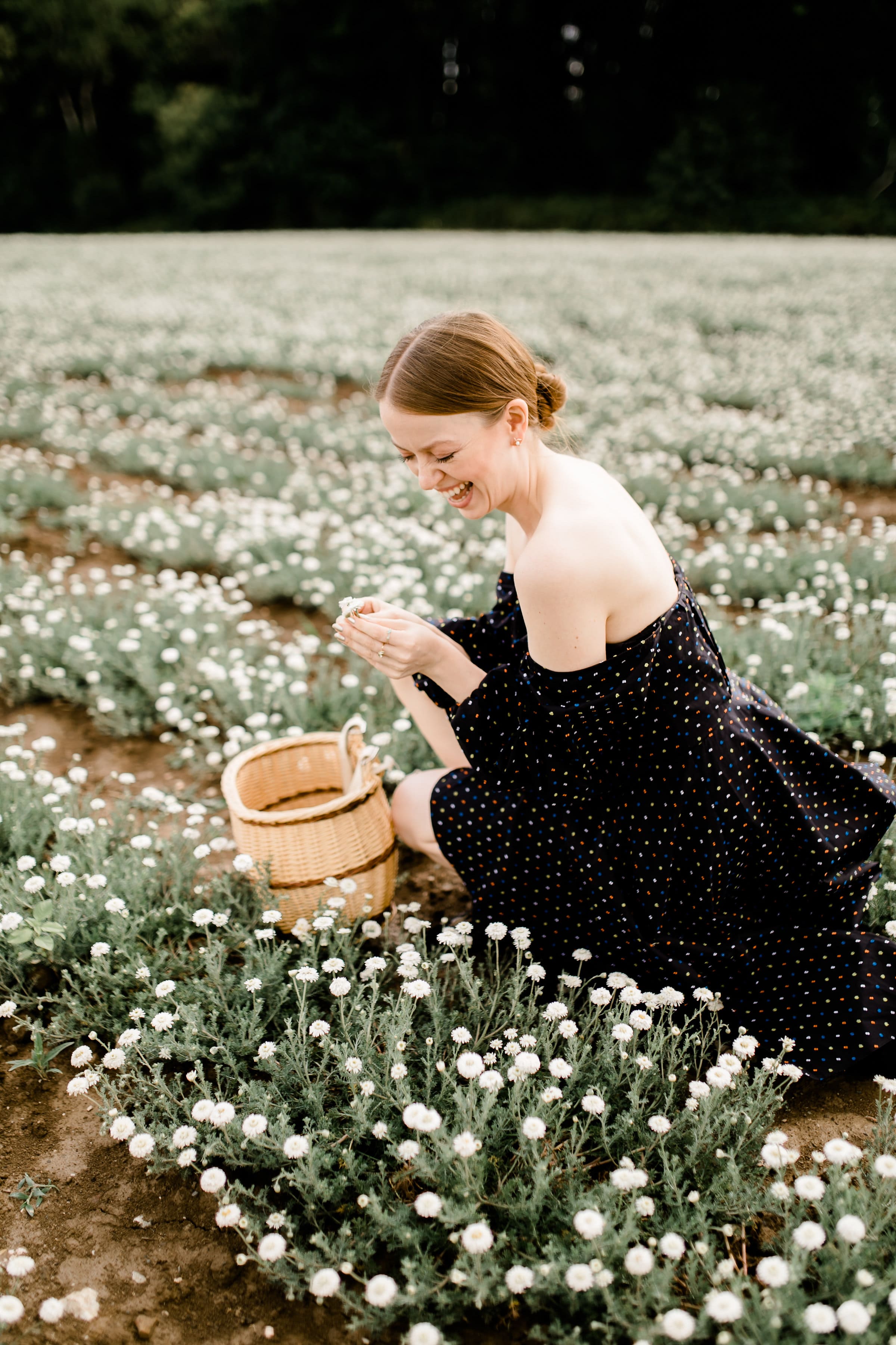 Jasmin kniet in einem blühenden Feld, trägt eine Blume in beiden Händen und lacht