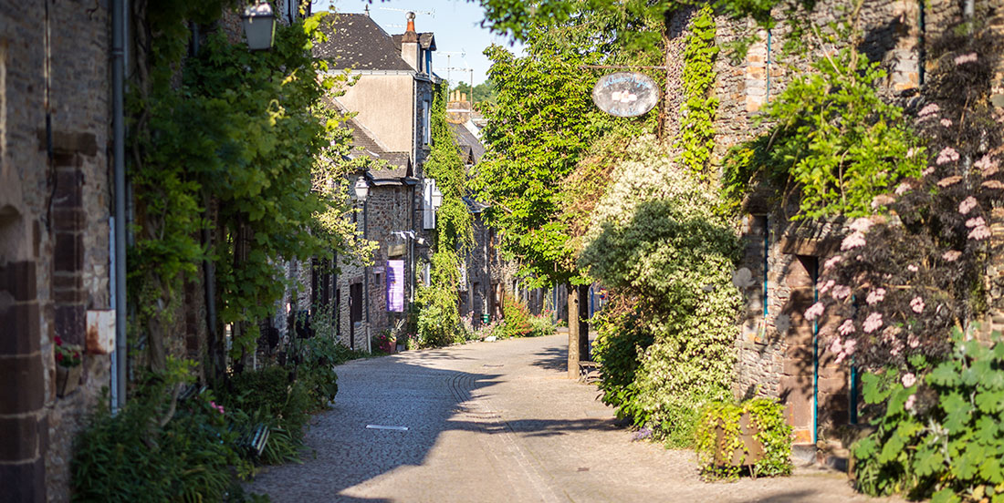 Eine malerische Gasse des Dorfs La Gacilly erstahlt im Glanz der Sonne und ist umgeben von grünen Pflanzen