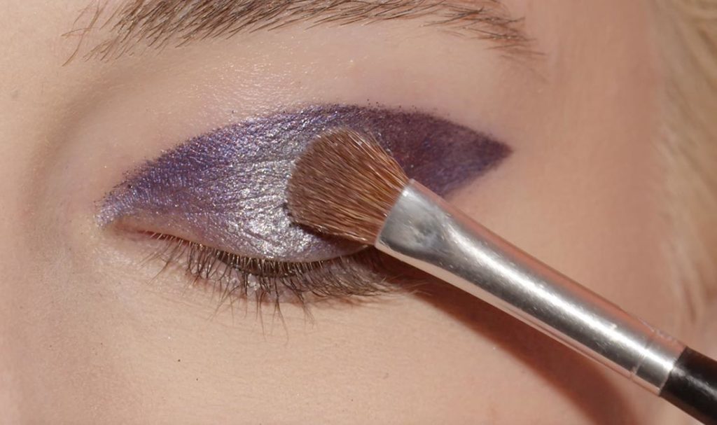 femme utilisant le pinceau de maquillage sur sa paupière