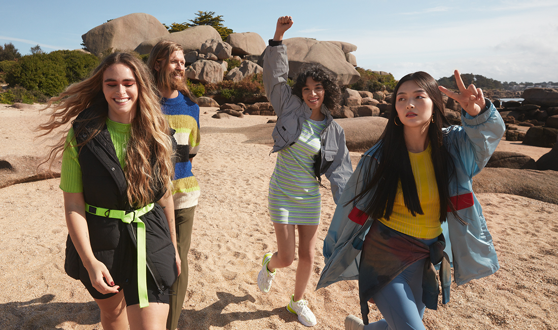 Group of women and men happily walking along beach shore feeling connected to nature by Yves Rocher