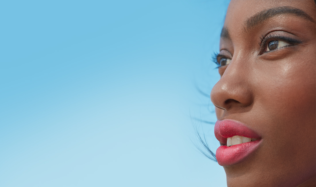 femme afro qui regarde à gauche le vent en face et sous un ciel bleu