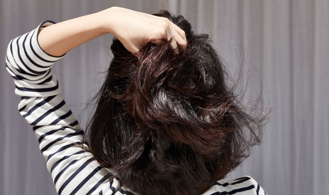 Femme brune vue de dos attrapant ses cheveux. sowimage