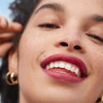 femme avec rouge à lèvre et dents blanches souriante avec du vent sur le visage yves rocher